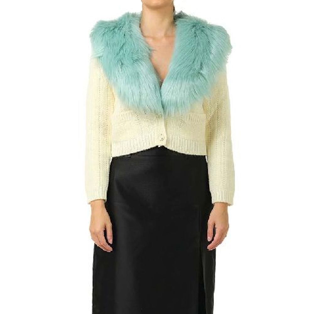 Cardigan en laine blanche Gucci, style élégant avec logo Gucci visible, porté sur un mannequin dans une scène intérieure.
