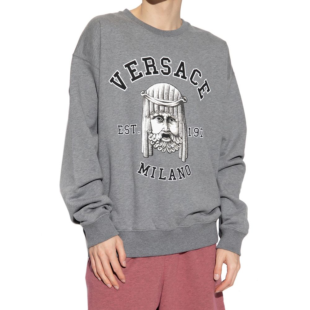 Sweatshirt gris en coton de la marque Versace, vue de face, avec logo emblématique sur la poitrine, tissu doux et confortable.