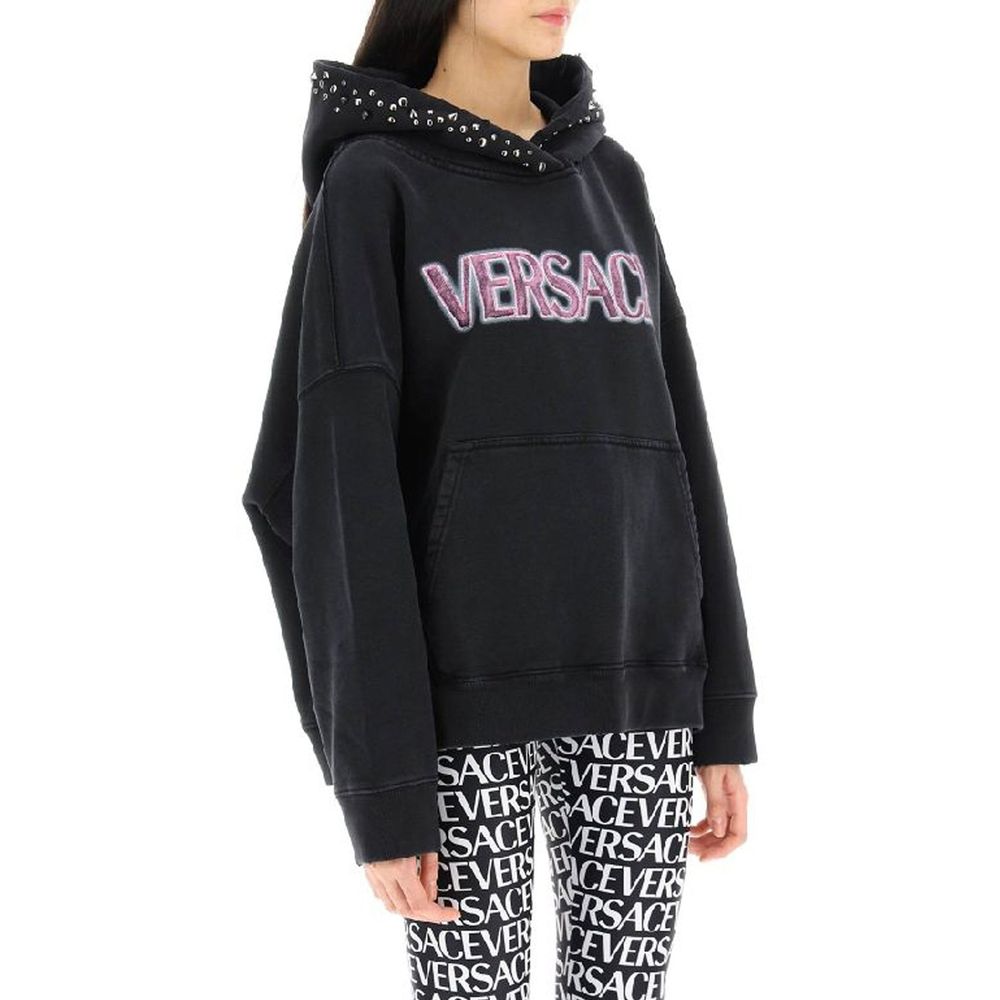 Sweatshirt en coton noir de la marque Versace, avec logo distinctif, porté de manière décontractée, vue de face.