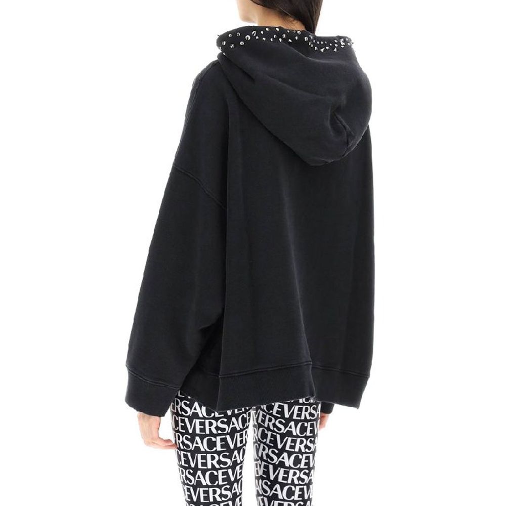 Sweatshirt en coton noir de la marque Versace, avec logo distinctif sur la poitrine, porté par un mannequin.