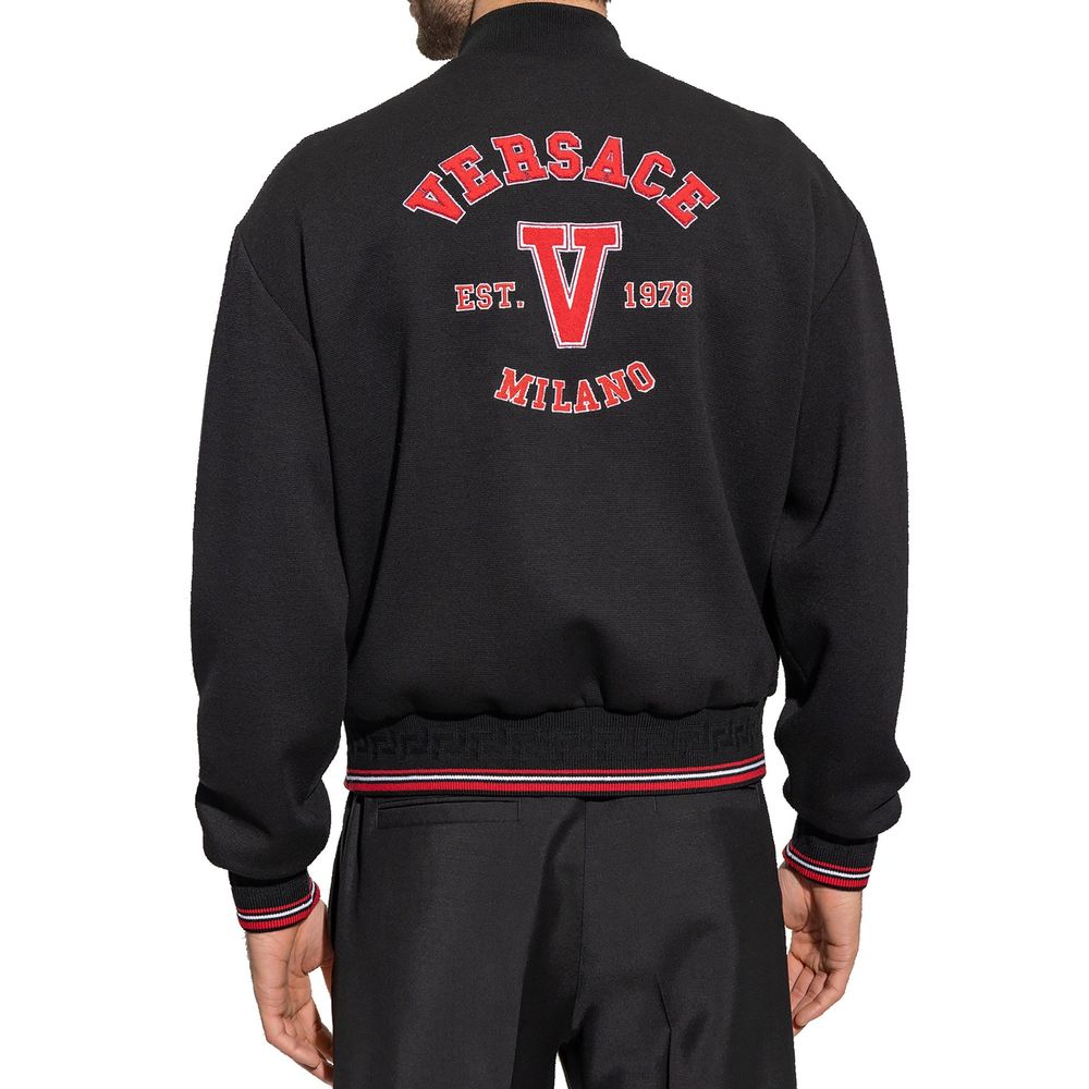 Veste bomber en laine vierge noire de Versace, style élégant avec logo Versace sur la poitrine, vue de face.