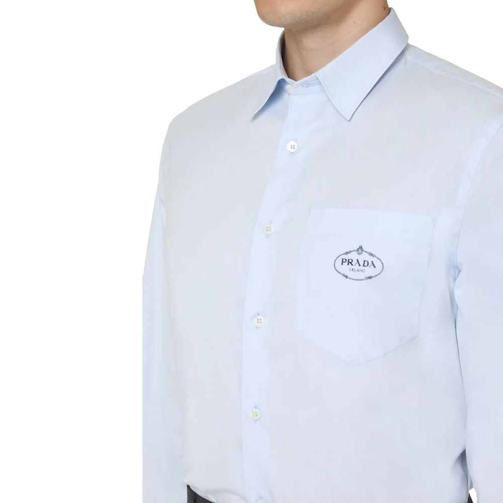 Chemise en coton bleue Prada pour homme, coupe élégante et détails raffinés, portée sur un mannequin.