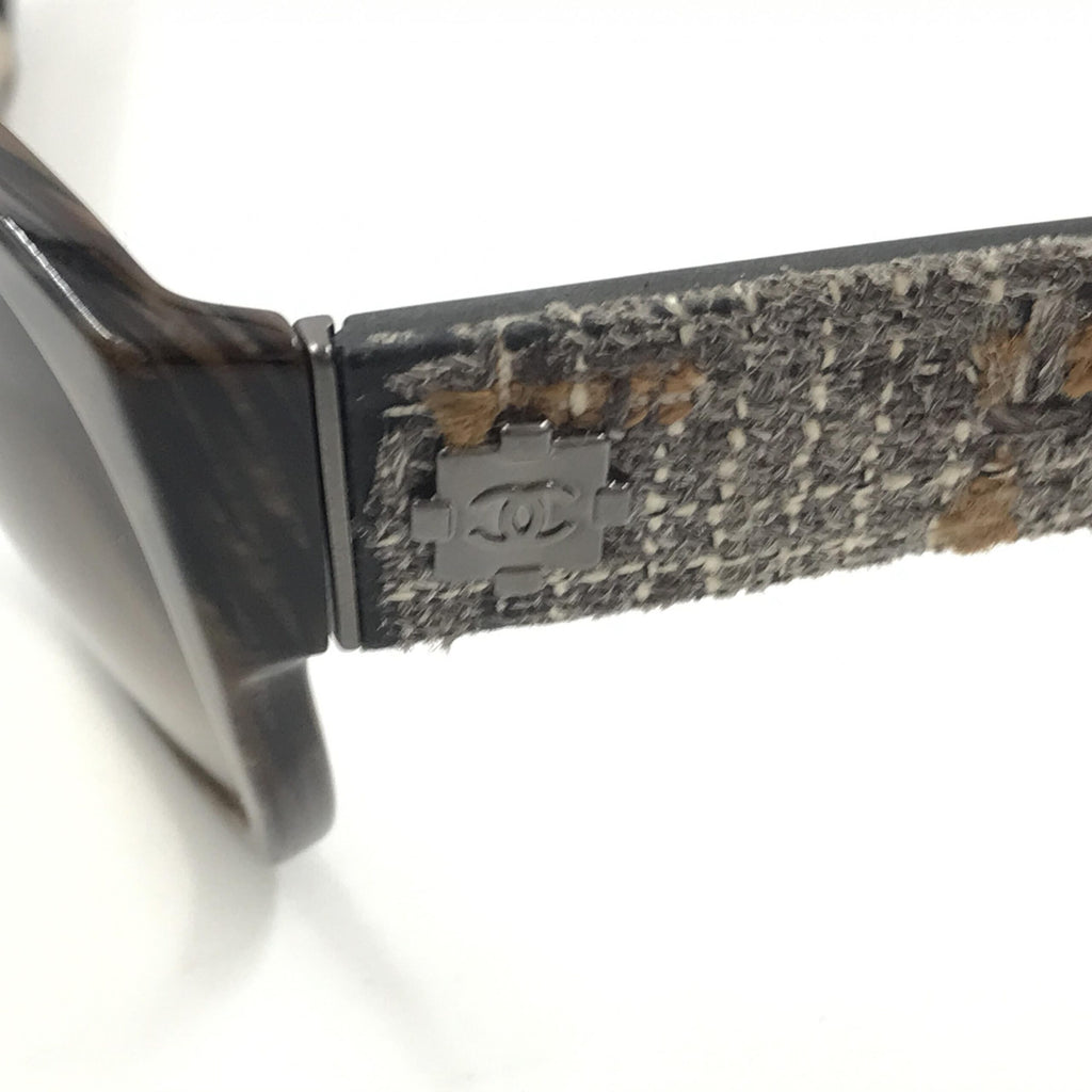 Lunettes de soleil Chanel avec monture marron et accents en tweed, style sophistiqué et élégant.