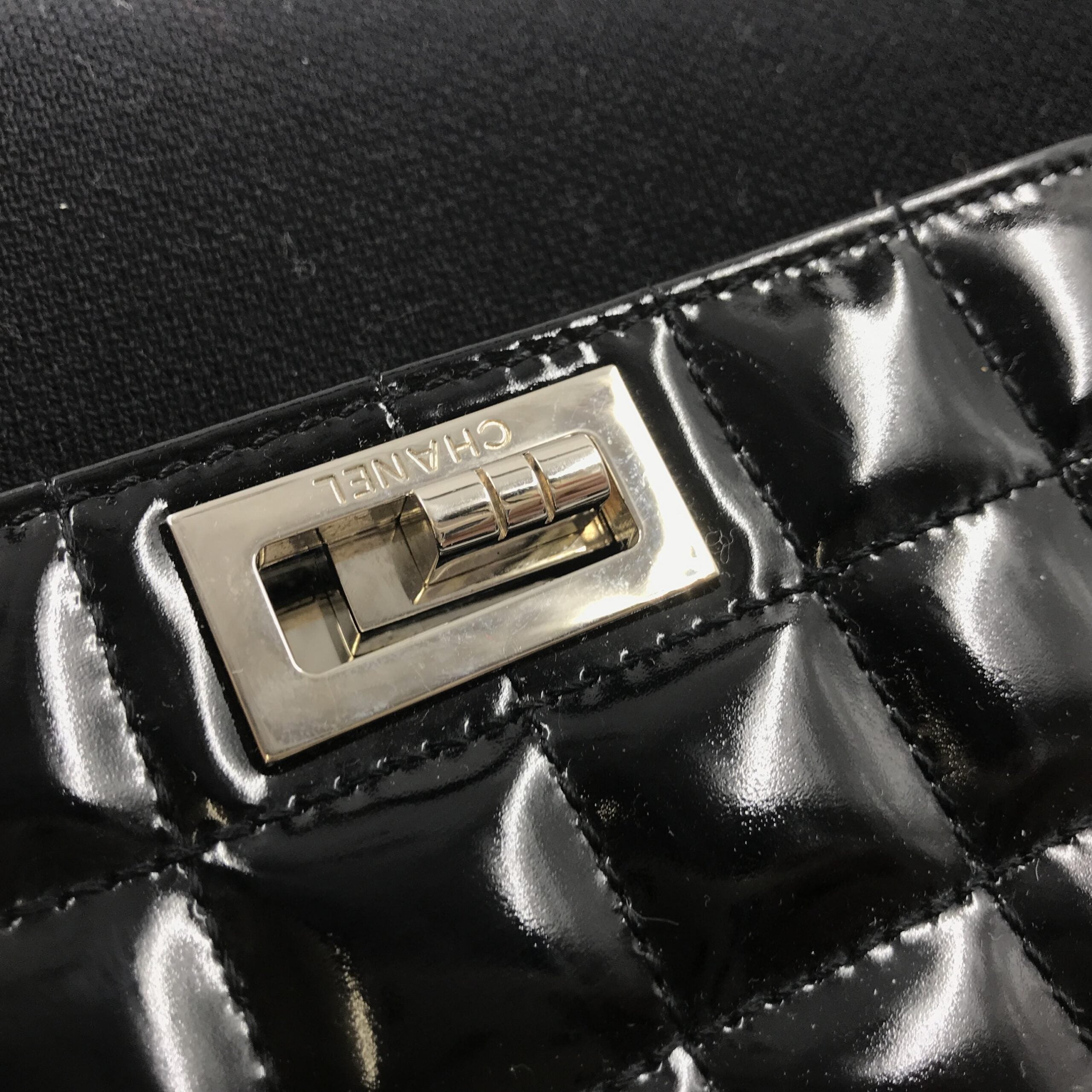 Sac Chanel en cuir verni chocolat, sac à bandoulière élégant avec logo emblématique, vue de face.