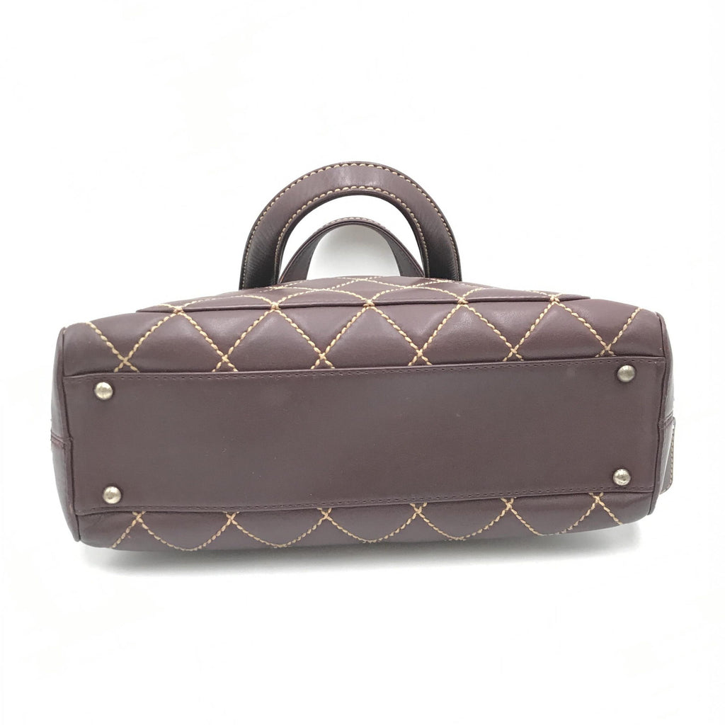 Sac à main Chanel Wild Stitch Mini Boston rouge avec détails en cuir, poignée en chaîne et logo Chanel visible.