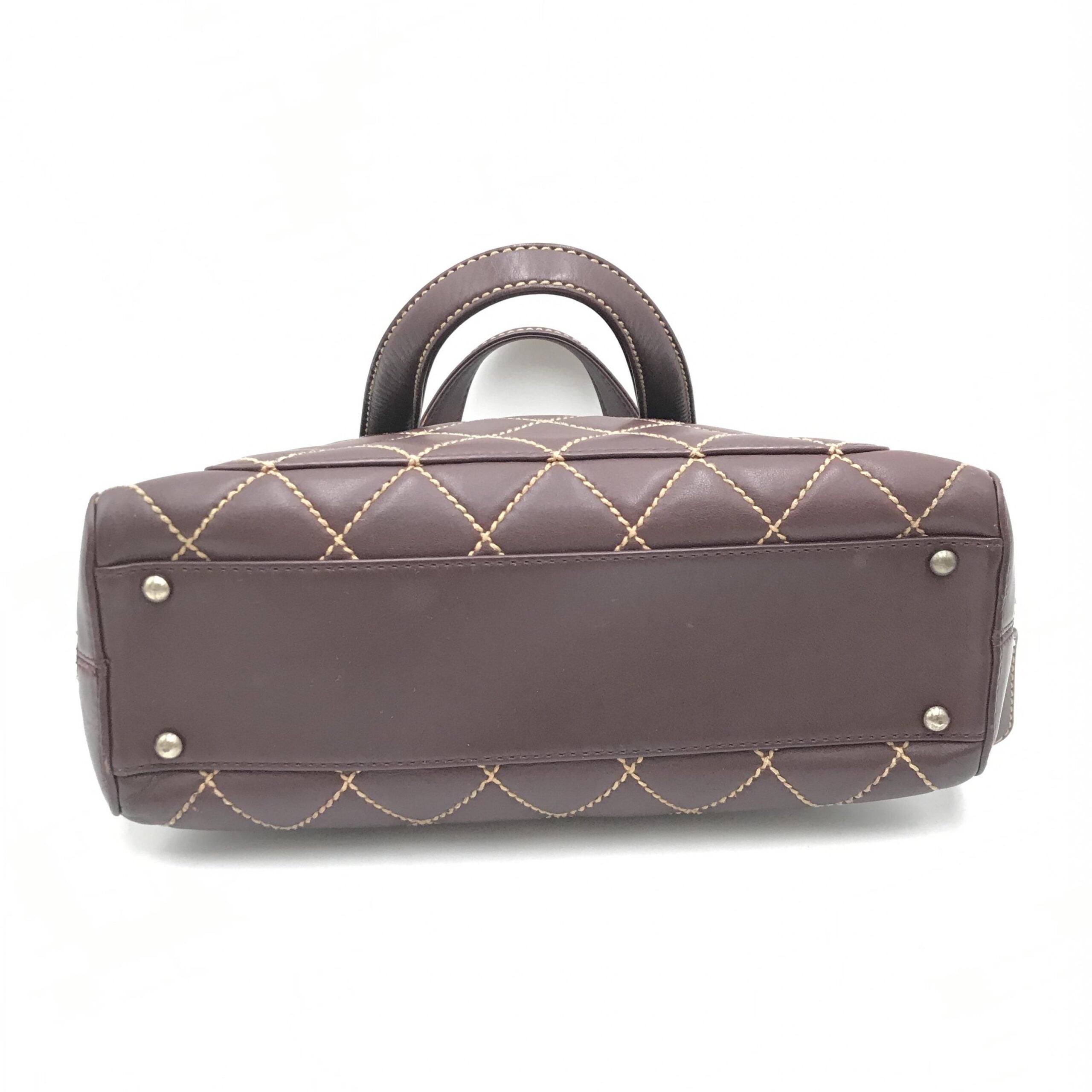 Sac à main Chanel Wild Stitch Mini Boston rouge avec détails en cuir, poignée en chaîne et logo Chanel visible.