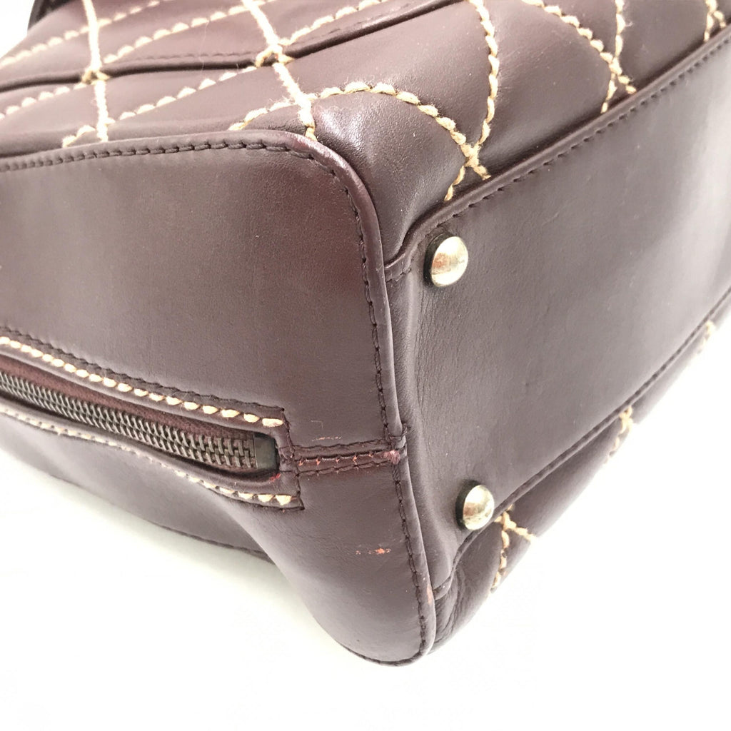 Sac à main Chanel Wild Stitch Mini Boston en cuir rouge, avec détails de couture distinctive et poignée en métal doré.