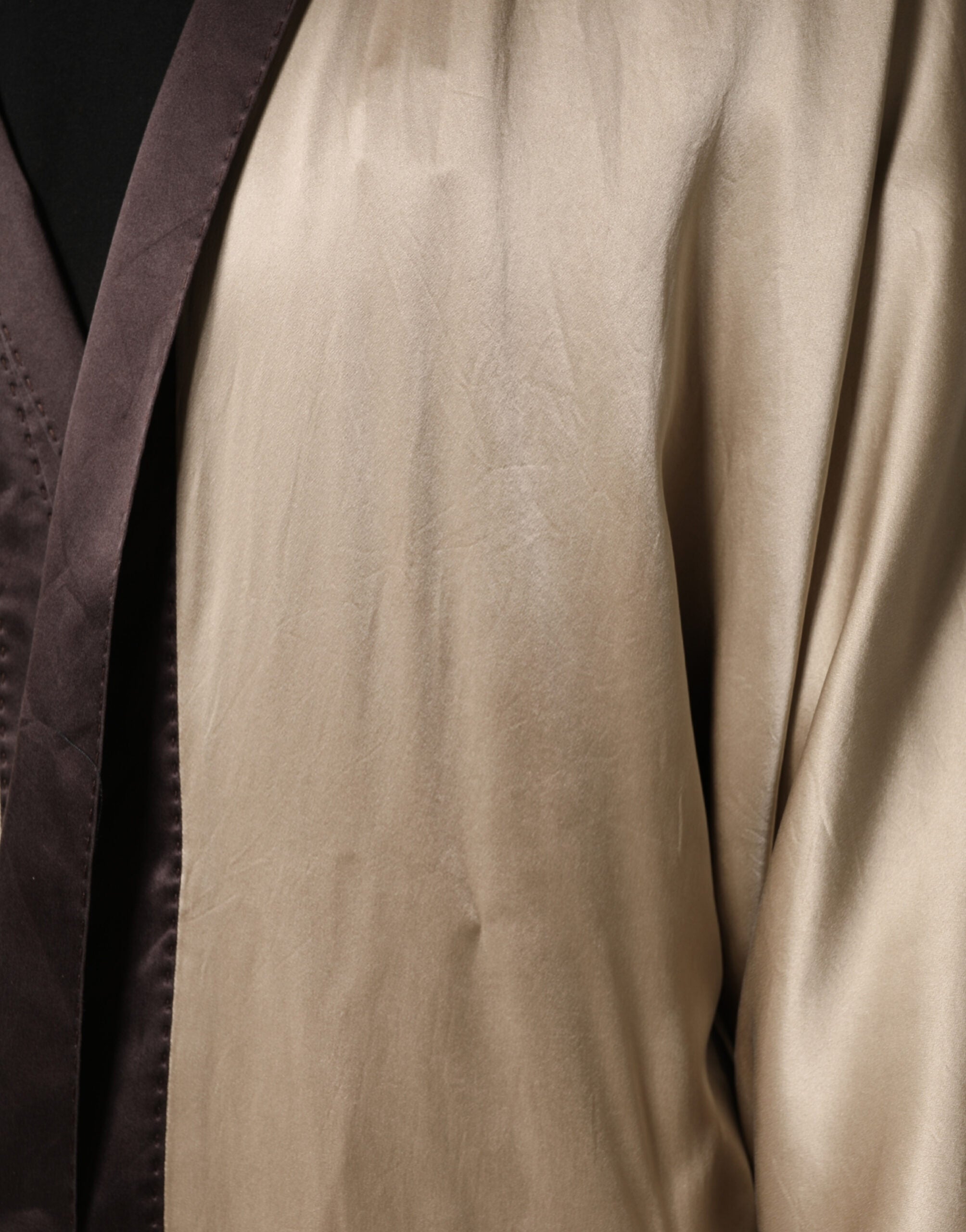 Longue robe manteau en soie satin beige de Dolce & Gabbana, élégante et sophistiquée, avec une coupe fluide et luxueuse.