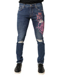 Jeans skinny Dolce & Gabbana à imprimé graffiti délavé et usé, en denim bleu avec détails distressed.