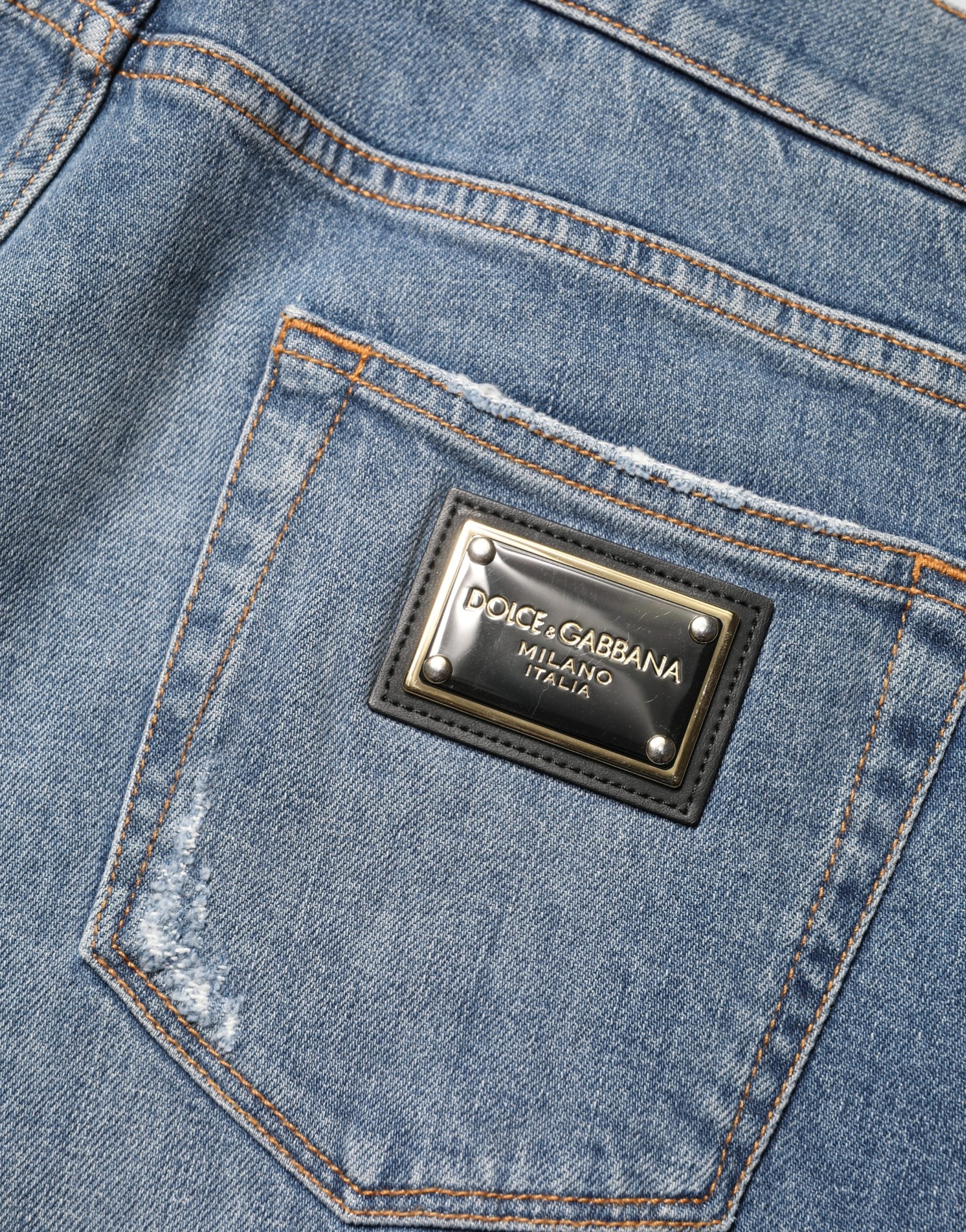 Jeans en denim coton bleu Dolce & Gabbana, coupe slim, déchirés, style tattered, visible sur l'image.
