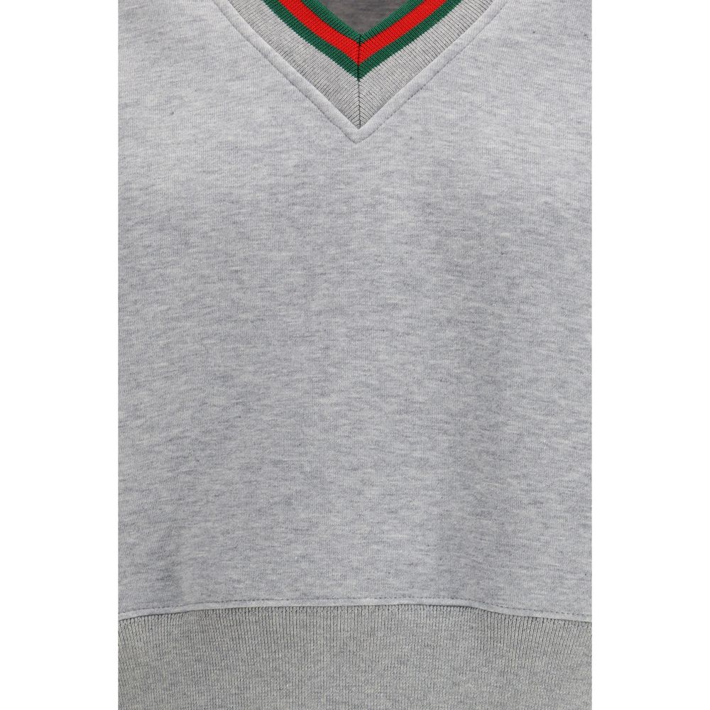 Sweat-shirt gris en coton de la marque Gucci, avec logo Gucci visible sur le devant, porté dans une ambiance décontractée.