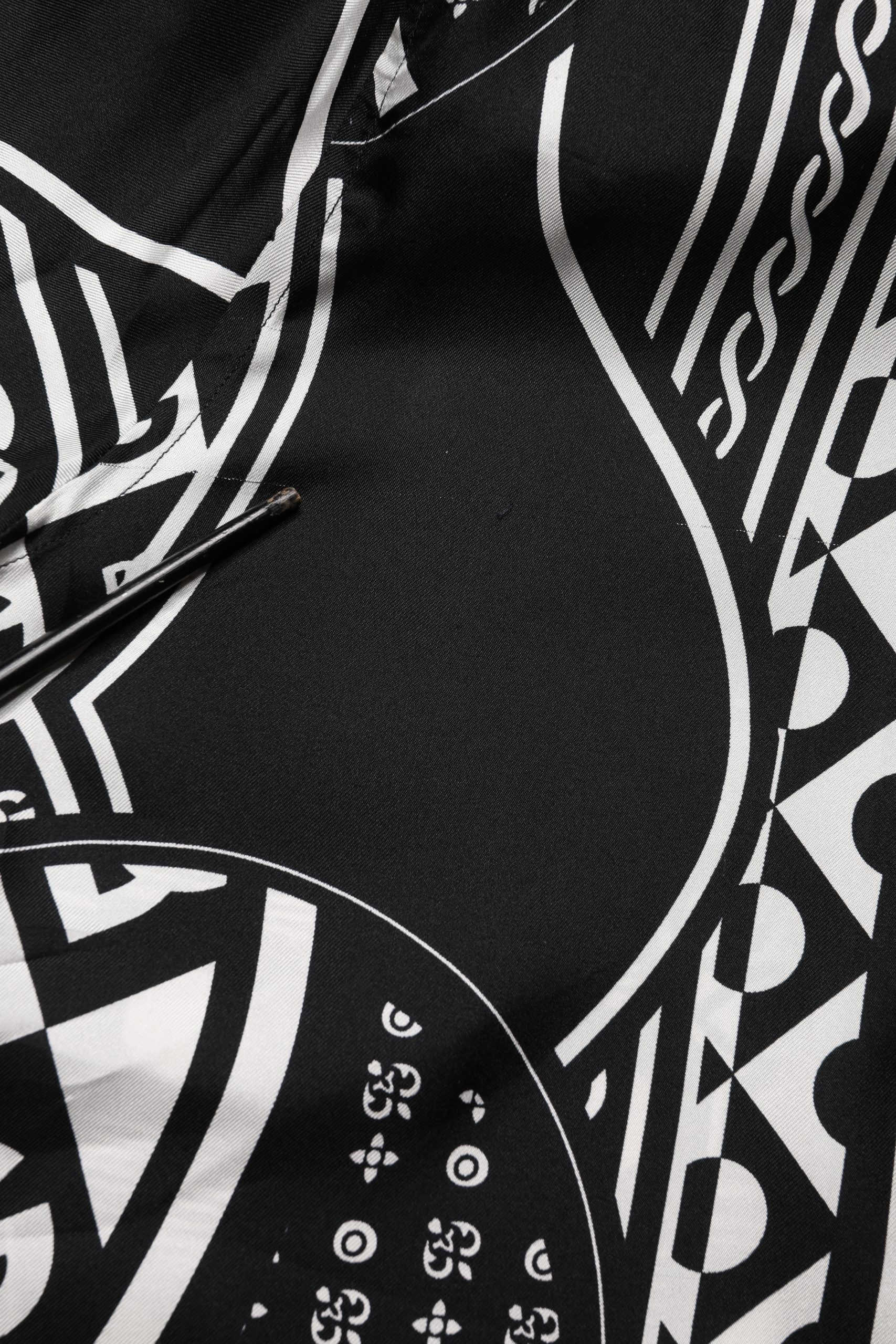 Chemise Dolce & Gabbana en soie noire à logo imprimé, manches courtes et style élégant visible sur l'image.