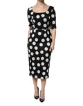 Robe midi en soie Dolce & Gabbana à pois noirs et blancs, coupe ajustée, élégante et fluide, portée avec manches longues.