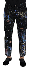 Jeans en denim noir Dolce & Gabbana avec imprimé éclaboussures de couleurs, coupe classique, détails de couture visibles.
