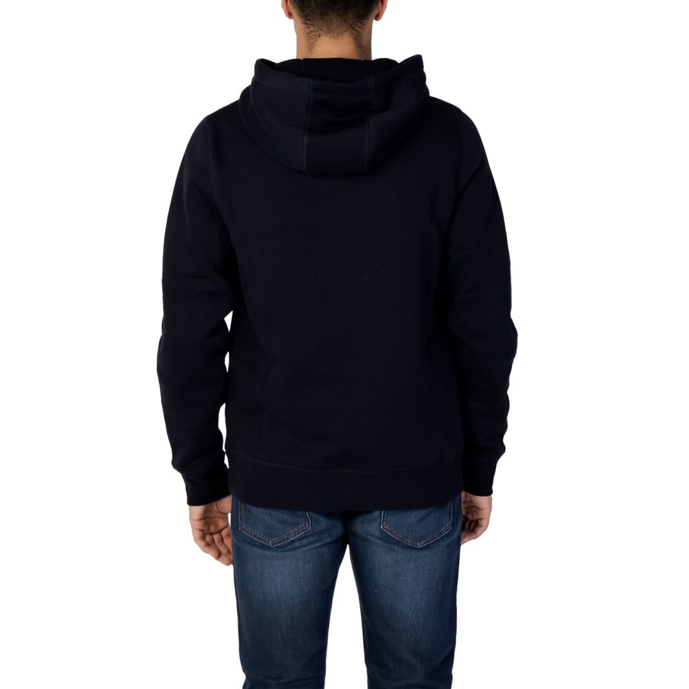 Sweat à capuche en coton bleu de la marque Tommy Hilfiger, avec logo sur la poitrine, porté par un mannequin.
