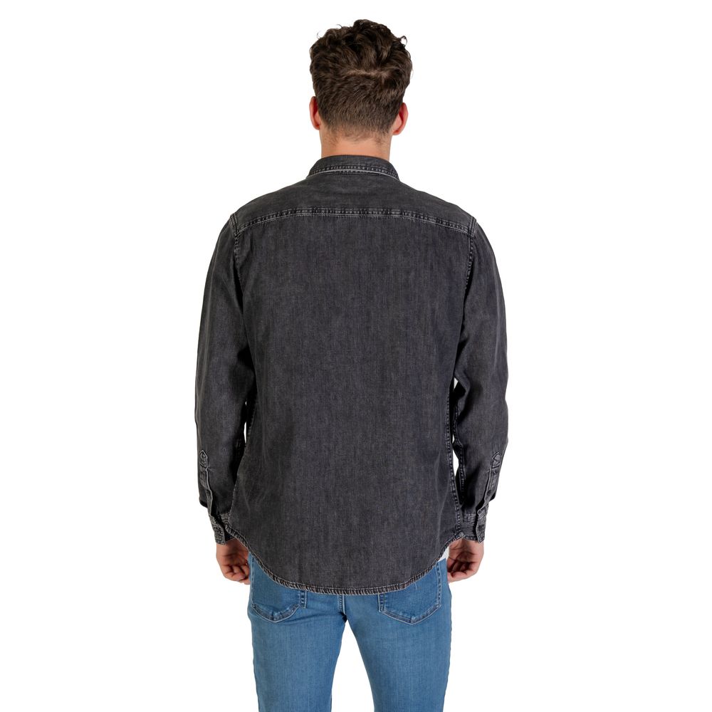 Chemise en denim noir Calvin Klein Jeans, coupe classique, avec boutons et col, portée sur un mannequin.