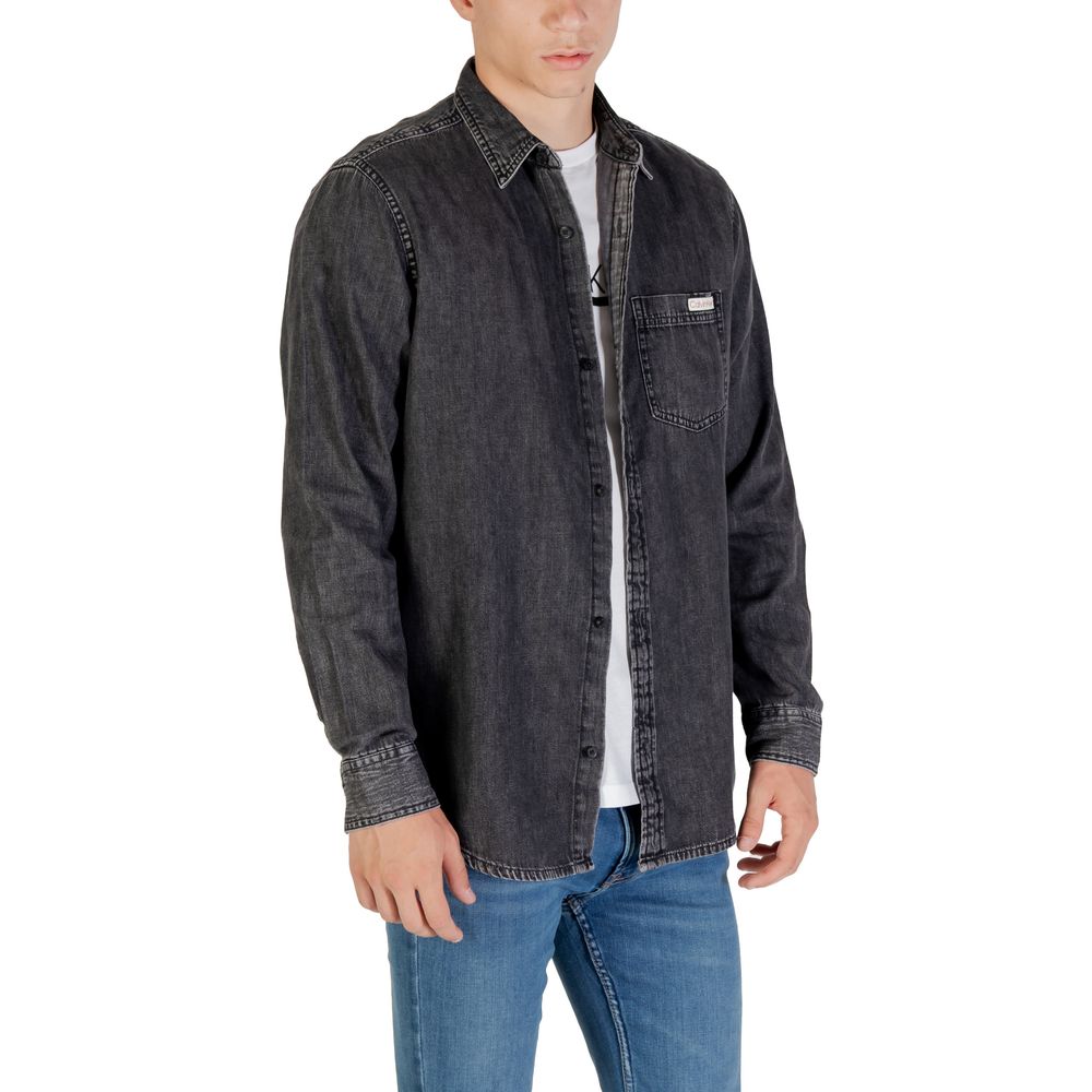 Chemise en denim noir Calvin Klein Jeans, style décontracté, avec boutons et poches avant, portée décontractée.