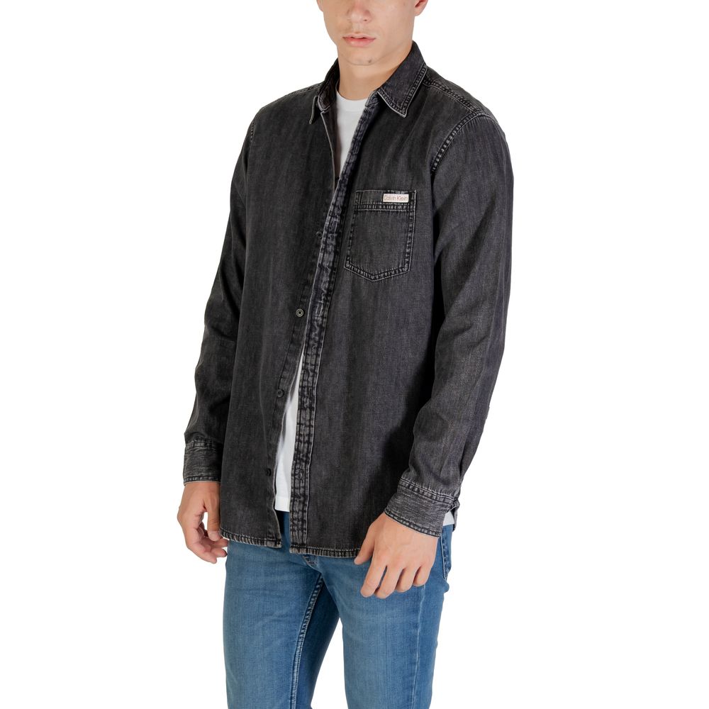 Chemise en denim noir Calvin Klein Jeans, coupe classique avec col et boutons, portée décontractée.