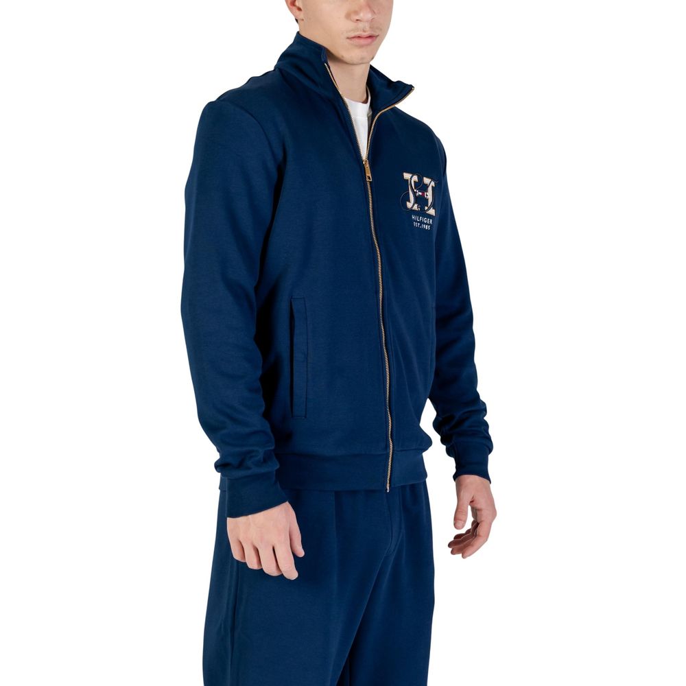 Sweatshirt en coton recyclé bleu Tommy Hilfiger, à capuche et logo sur la poitrine, portée sur un modèle.