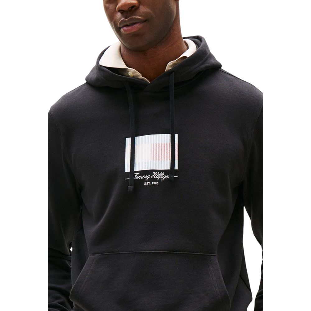 Sweat à capuche Tommy Hilfiger en coton recyclé noir, vue de face avec logo branding visible.