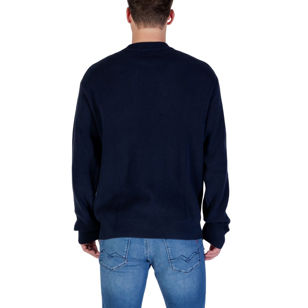 Sweat-shirt bleu en coton de la marque Calvin Klein Jeans, porté, avec logo discret visible sur le devant.