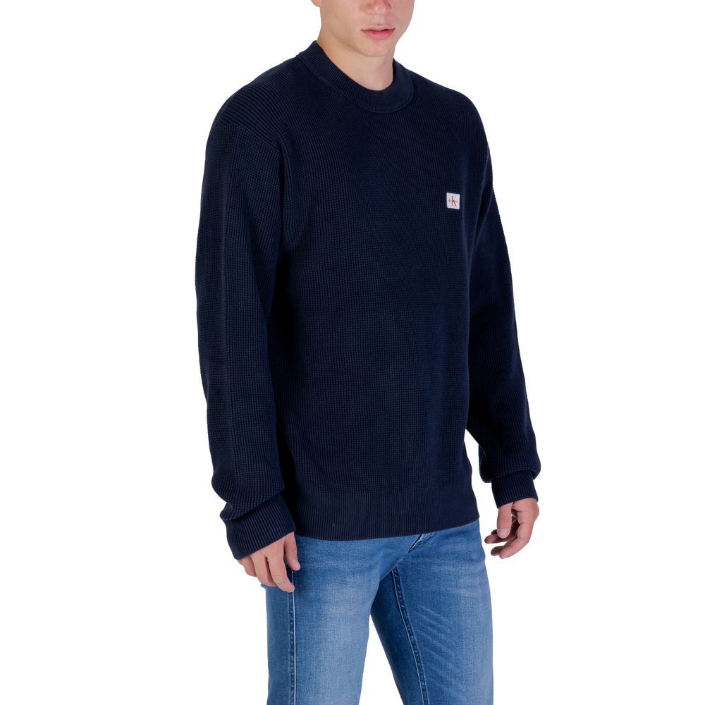 Sweatshirt en coton bleu de Calvin Klein Jeans, coupe décontractée, logo discret sur la poitrine, porté sur un mannequin.