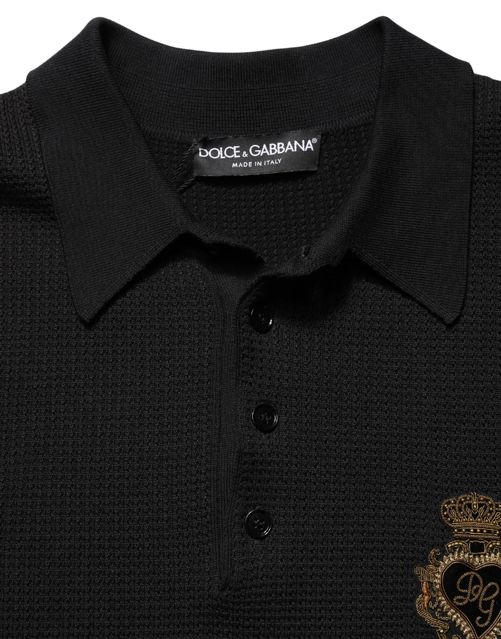 Polo en soie noir Dolce & Gabbana avec écusson héraldiques brodé, détail élégant et sophistiqué.