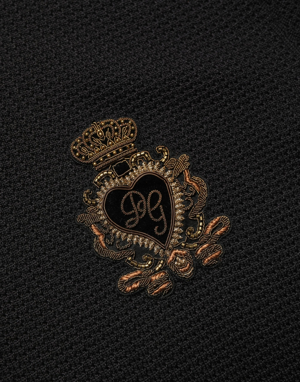 Polo en soie noir Dolce & Gabbana avec broderie d'écu héraldique, patch orné sur la poitrine, style élégant et sophistiqué.