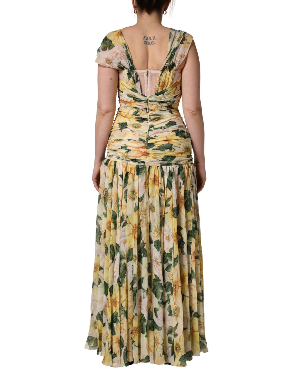 Robe longue plissée en soie jaune à imprimé floral Dolce & Gabbana, élégante et fluide, portée avec des détails sophistiqués.