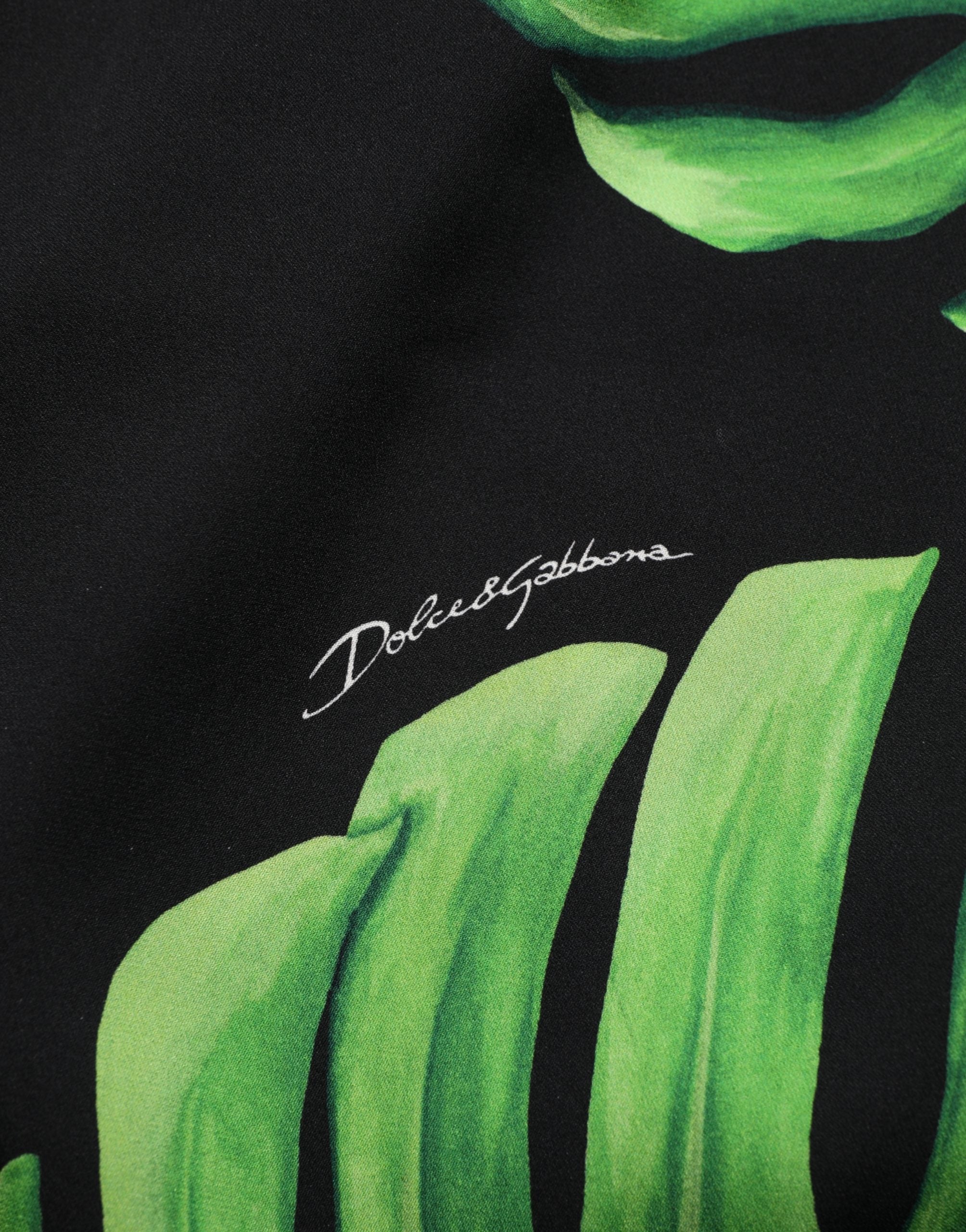 Chemisier en soie noir Dolce & Gabbana avec motif de philodendron, détails élégants et coupe fluide visible sur l'image.
