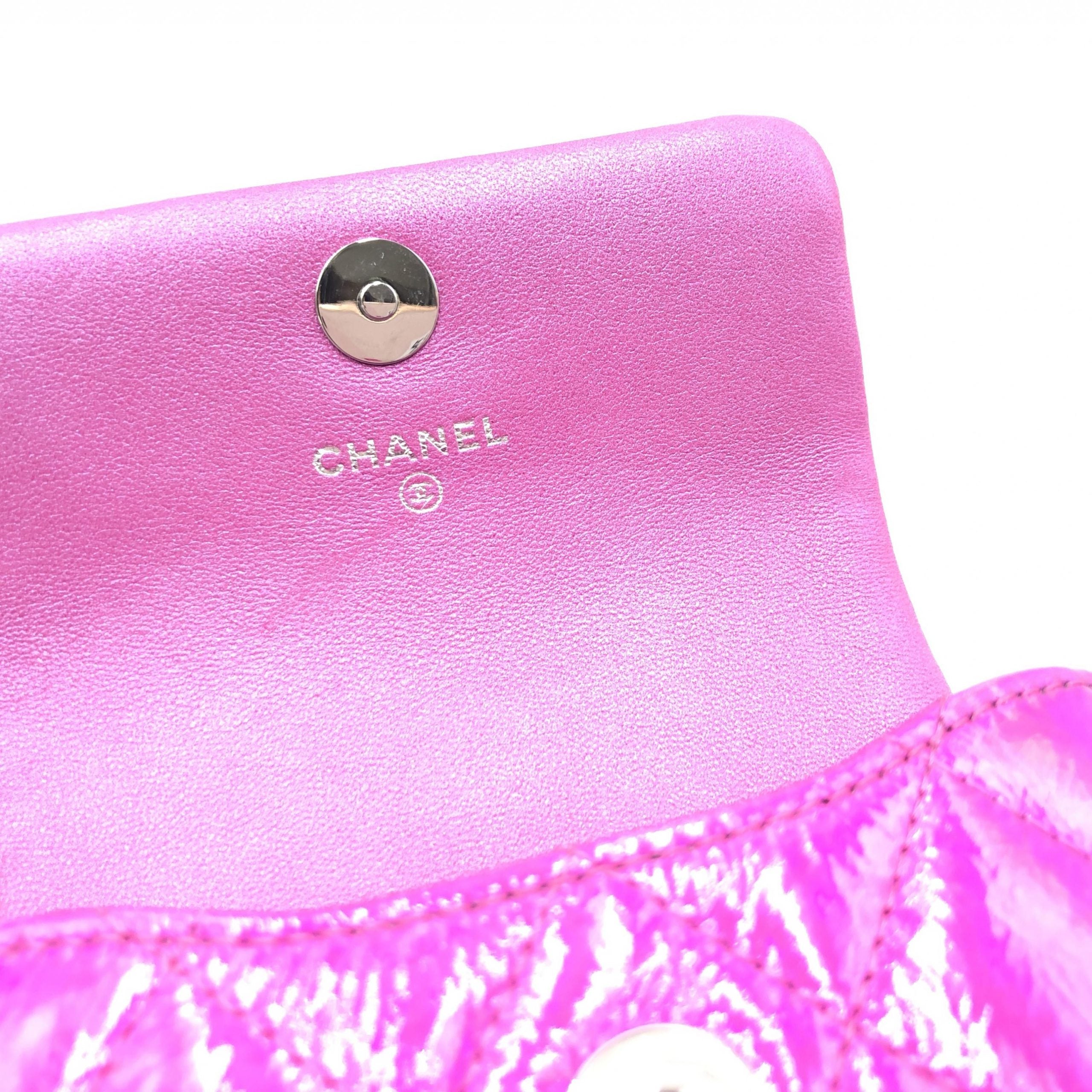 Pochette en cuir matelassé rose irisé de Chanel, finition brillante, avec doublure intérieure visible, style élégant et sophistiqué.