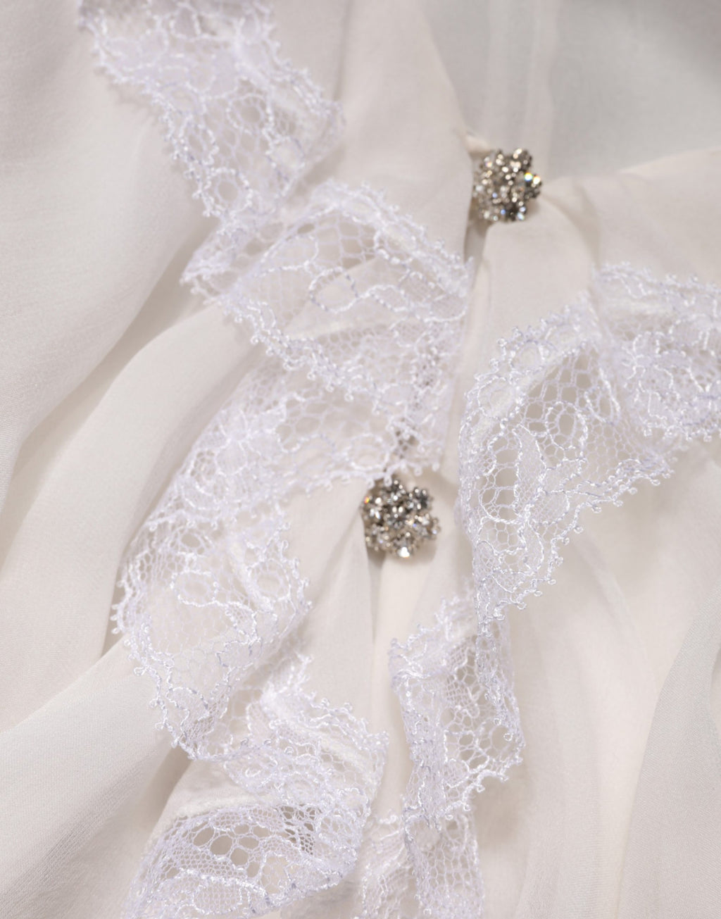 Blouse blanche Dolce & Gabbana à manches longues, ornée de dentelle et de volants pour un style élégant et féminin.