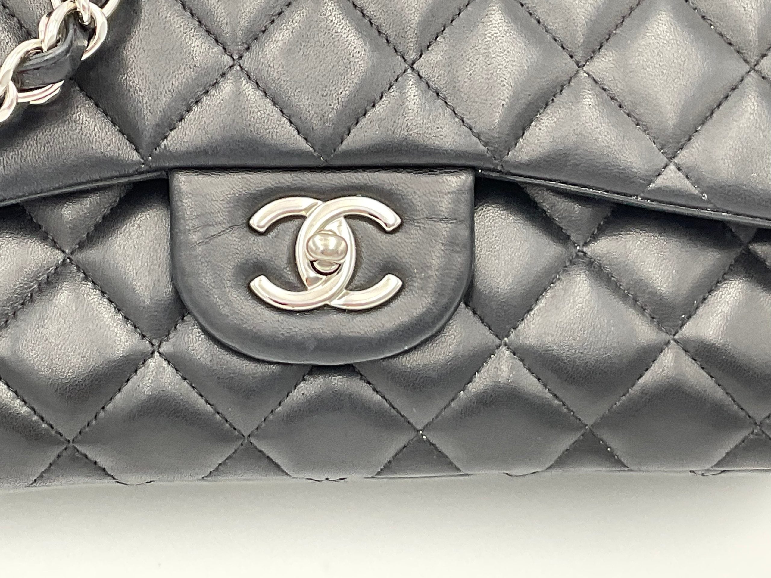 Sac Chanel Timeless Classique Jumbo en cuir noir avec matelassage et fermoir en métal doré, porté à la main.