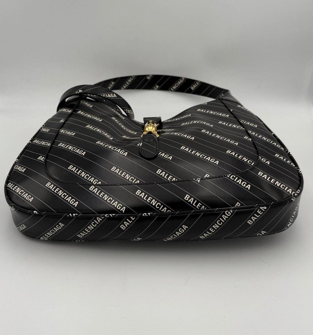 Sac à main Gucci Jackie 1961 en cuir noir avec détails dorés et bandoulière, style élégant et classique.
