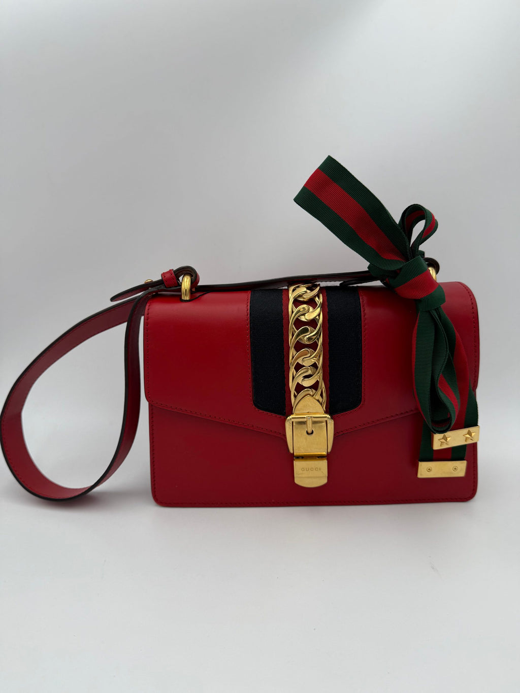 Sac à main Gucci Sylvie rouge avec détails en cuir et chaîne dorée, accessoire élégant pour femmes.