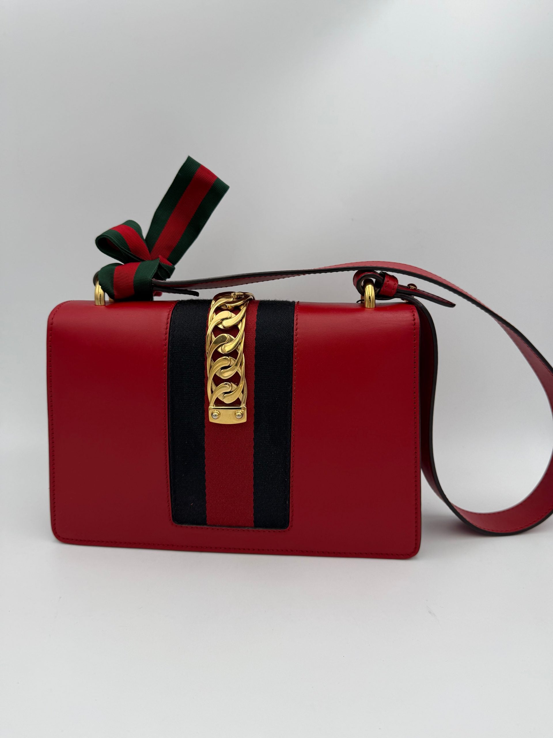 Sac à main Gucci Sylvie rouge avec chaîne en métal, design élégant et sophistiqué, idéal pour compléter une tenue chic.