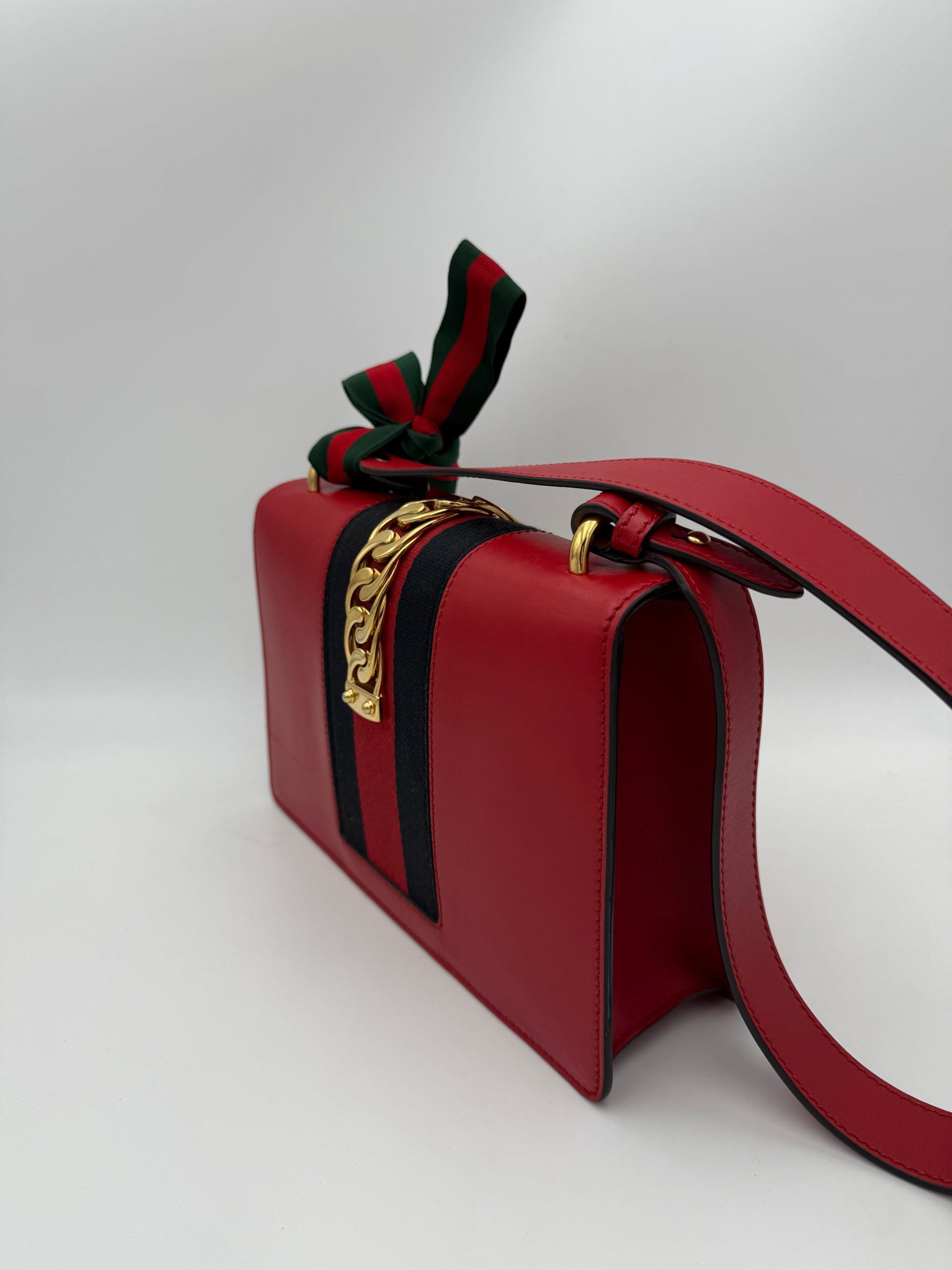 Sac à main Gucci Sylvie rouge avec poignées en cuir et détails métalliques, élégant et tendance.