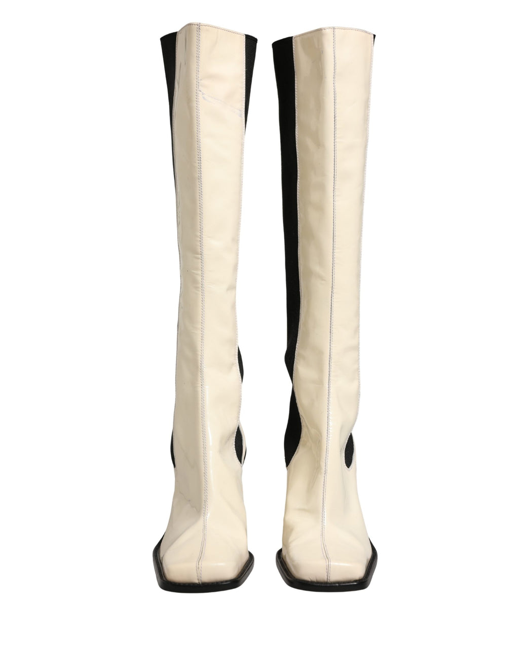 Bottes en cuir blanc et noir Dolce & Gabbana, cuissardes élégantes avec talons, visibles en détail sur l'image.