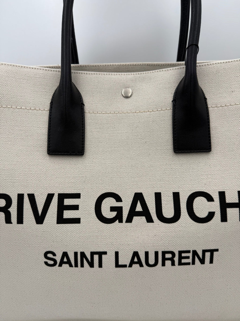 Grand sac cabas Saint Laurent Rive Gauche, en toile noire avec logo, idéal pour un style élégant et pratique.