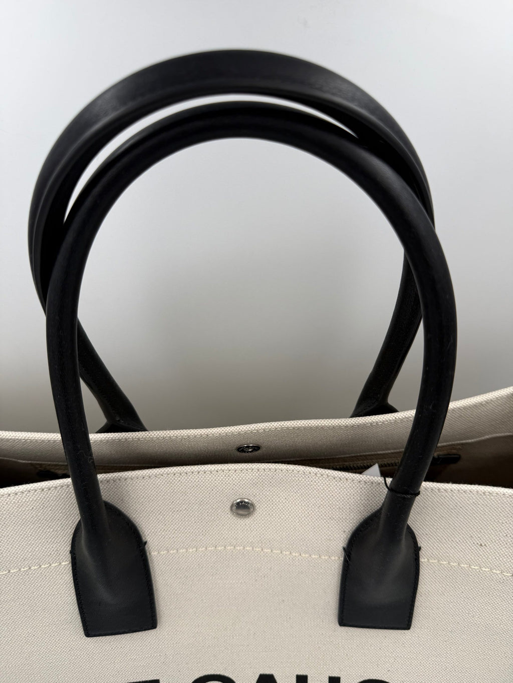 Grand sac cabas Saint Laurent Rive Gauche en toile avec poignées en cuir et logo emblématique sur le devant.