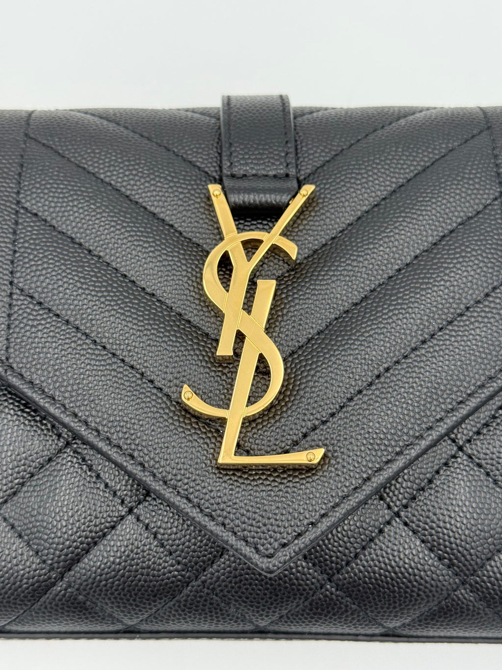 Sac à main Saint Laurent enveloppe petite en cuir grainé noir, élégant et compact, avec fermeture sophistiquée.