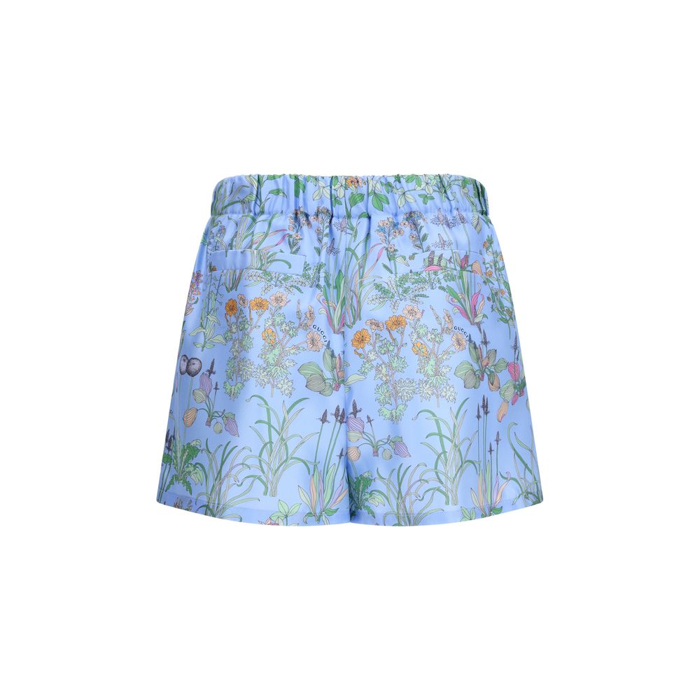Shorts bermuda en soie bleue de Gucci, style élégant avec logo Gucci visible, tissu fluide et finition soignée.