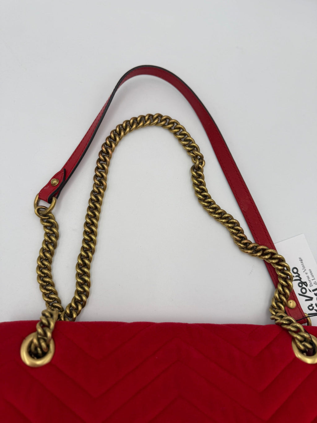 Sac à main Gucci Marmont en velours rouge, sac à main élégant avec chaîne en or et logo Gucci visible.