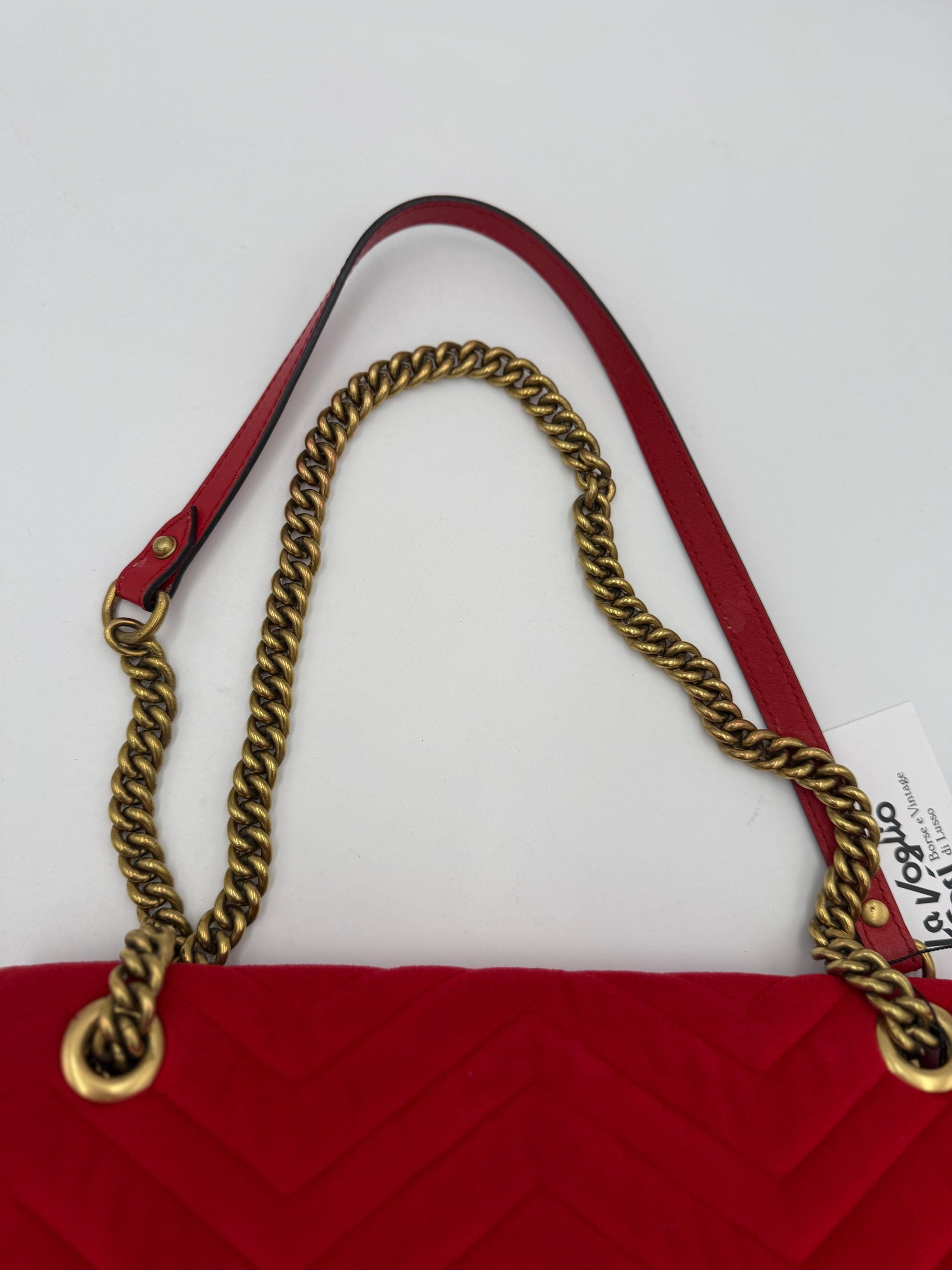 Sac à main Gucci Marmont en velours rouge, sac à main élégant avec chaîne en or et logo Gucci visible.