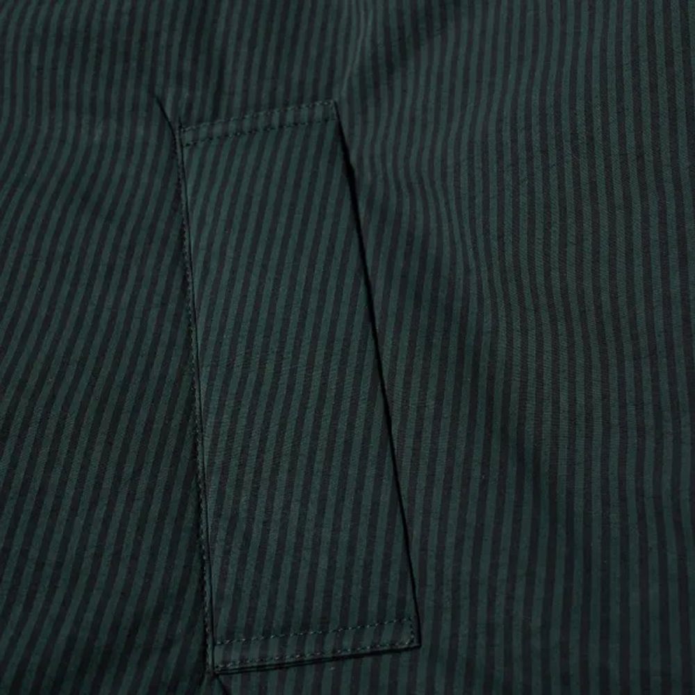 Veste longue en coton noir de Balenciaga, design épuré et moderne, visible en gros plan sur fond neutre.