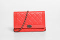 Portefeuille Chanel Boy en cuir d'agneau rouge avec chaîne, élégant et sophistiqué, visible en détail dans cette image.