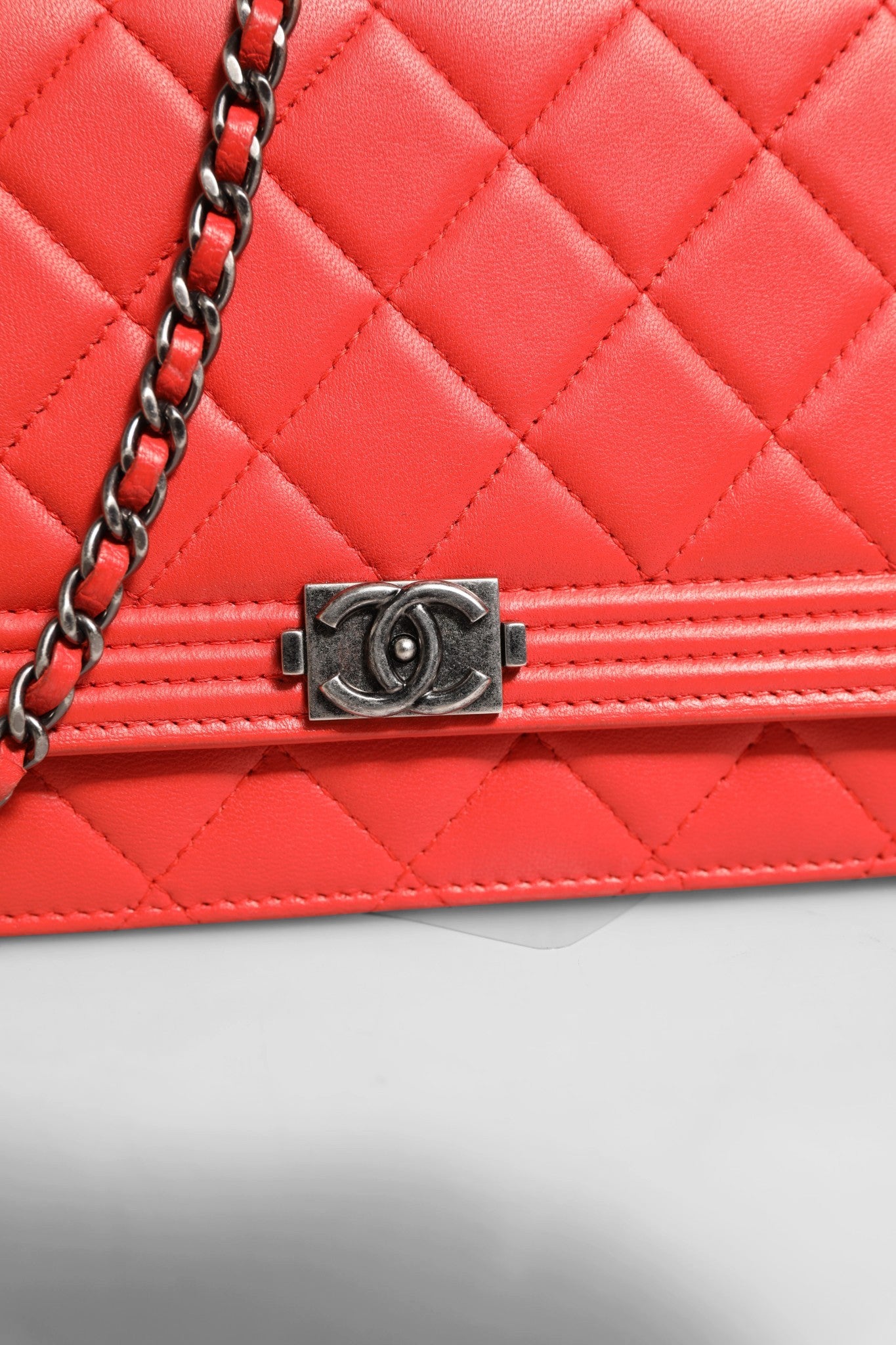 Portefeuille Chanel Boy en cuir de lambskin rouge avec chaîne, élégant et compact, idéal pour un style sophistiqué.