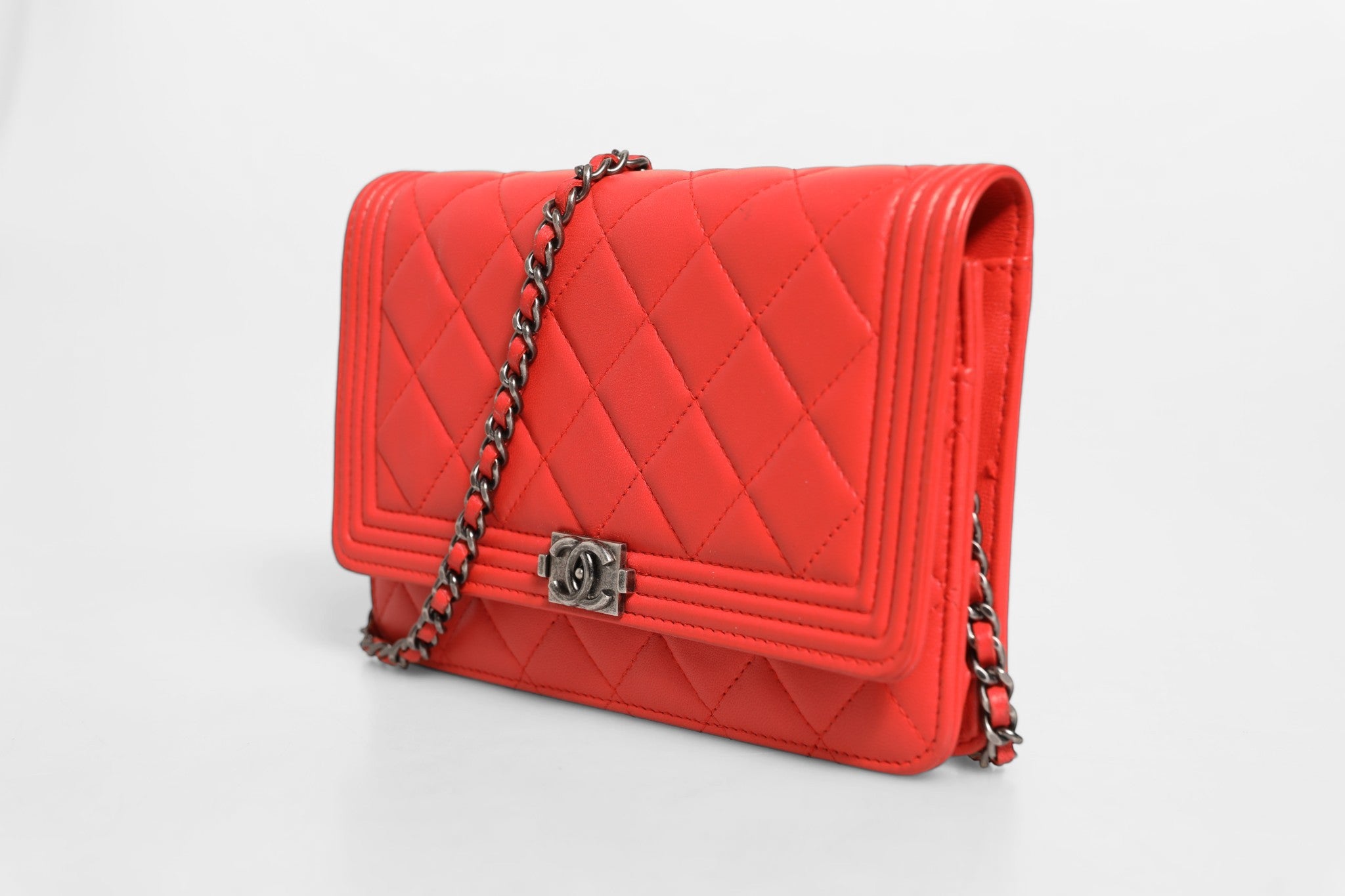 Portefeuille Chanel Boy en cuir d'agneau rouge avec chaîne, élégant accessoire de luxe pour femme.