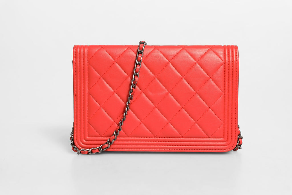 Portefeuille Chanel Boy en cuir d'agneau rouge avec chaîne, élégant et moderne, conçu pour un style sophistiqué.
