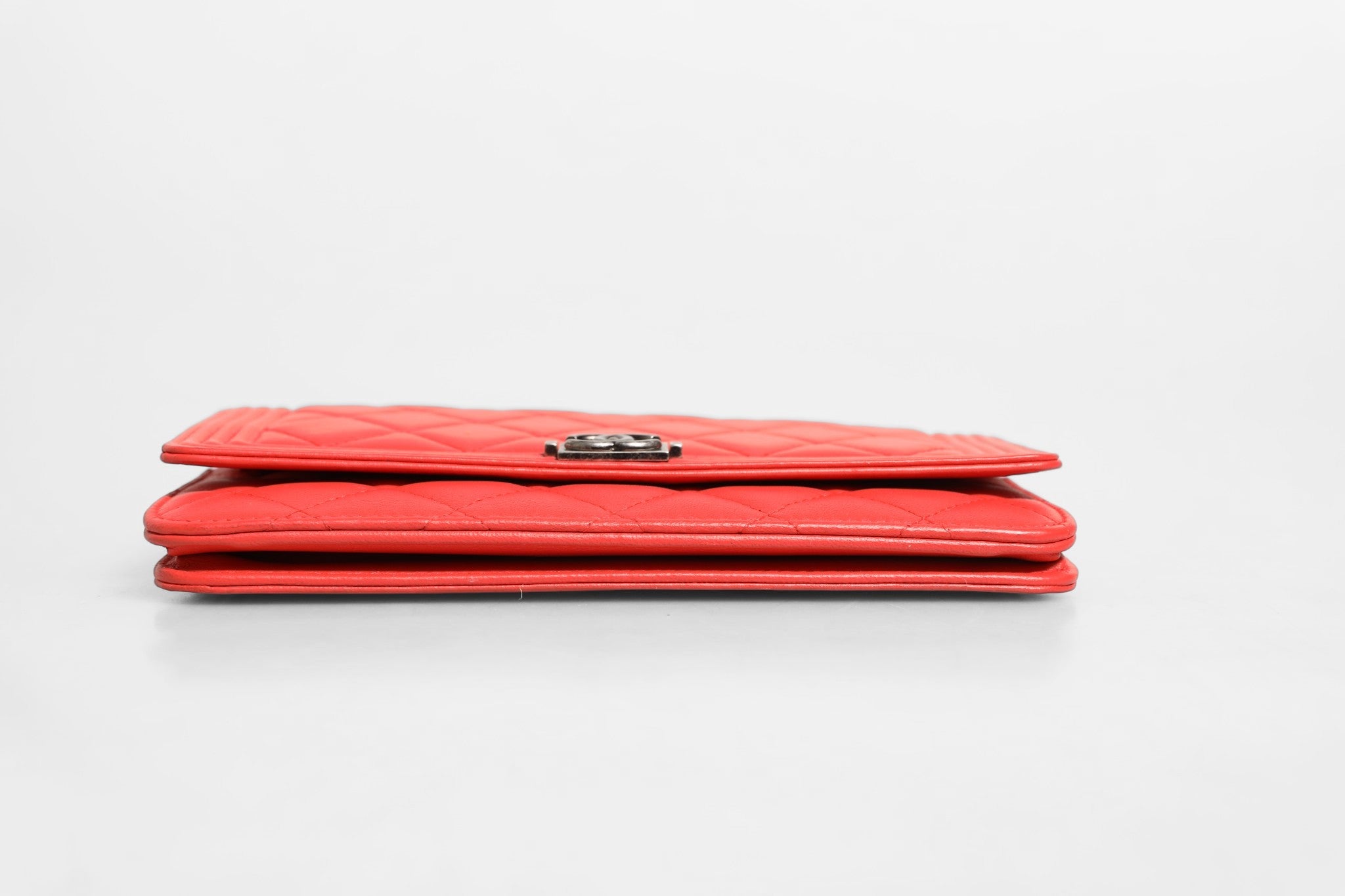 Portefeuille Chanel Boy en cuir d'agneau rouge avec chaîne, élégant accessoire de maroquinerie de luxe.